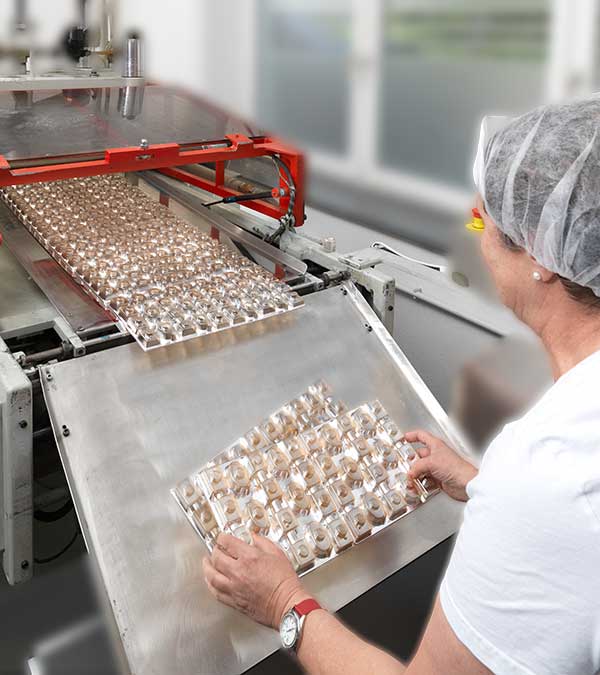 Frau arbeitet an Tiefziehmaschine